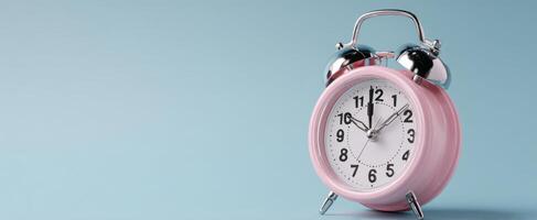 The charming pink alarm clock standing on a pastel blue background. photo