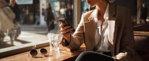 The woman enjoying sunlight while using her smartphone in a cozy cafe. photo