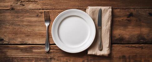 The elegant empty plate set on a rustic wooden table with cutlery. photo