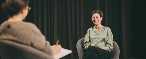 The female interviewee smiling during a professional conversation on stage. photo