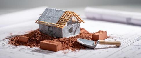The miniature house model on construction plans with tools and materials. photo