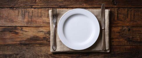 The elegant white plate set on a rustic wooden dining table. photo