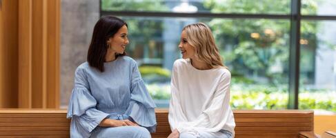 The two stylish women enjoy a light-hearted conversation in a modern space. photo