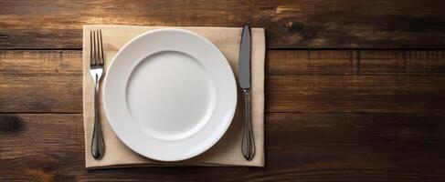 The elegant dining setting with a white plate and cutlery on a wooden table. photo