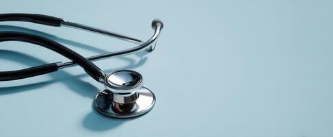 The stethoscope resting on a pastel blue surface for medical examination purposes. photo