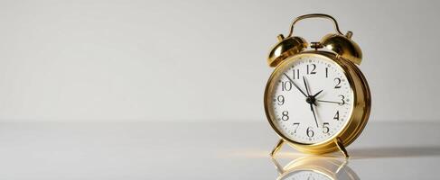The classic gold alarm clock on a reflective surface, symbolizing time management. photo