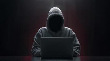 The hooded figure using a laptop in a mysterious dark environment. photo