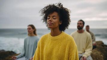 The serene group of individuals meditating by the beautiful ocean shore. photo