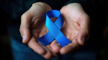 The blue ribbon held in hands symbolizing awareness and support for important causes. photo