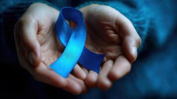 The blue awareness ribbon held gently in hands symbolizing support and hope. photo