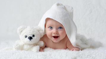 The baby with a teddy bear wrapped in a cozy blanket smiling joyfully. photo