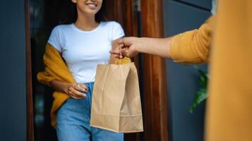 The woman receiving a delivery bag at her home doorway with a smile. photo