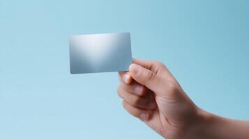 The hand holding a blank card against a soft blue background. photo