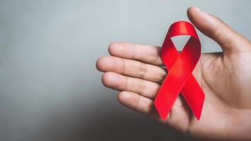 The hand holding a red ribbon symbolizes awareness and support for important causes. photo