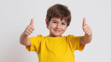 The cheerful boy giving a thumbs-up with a big smile in a yellow shirt photo