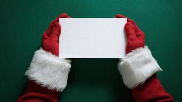 The festive Santa hands holding a blank greeting card ready for your message. photo