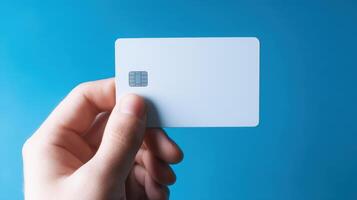 The hand holding a blank payment card against a blue background. photo