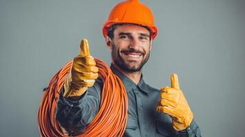 The smiling electrician giving a thumbs-up with electrical cables and safety gear. photo