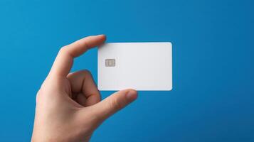 The hand holding a blank white card against a blue background. photo