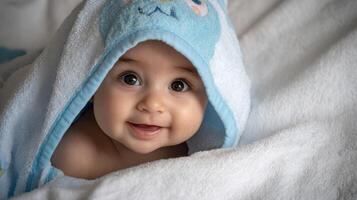 The adorable baby smiling warmly from within a cozy hooded towel. photo