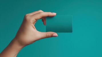 The hand holding a blank card against a teal background photo