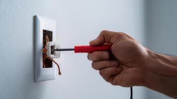 The electrician testing wires with a screwdriver in a residential outlet. photo