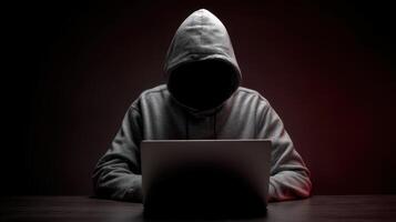 The hooded figure working secretly on a laptop in a dark environment. photo
