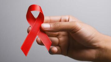 The hand holding a red ribbon symbolizing health awareness and support. photo