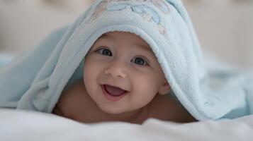 The joyful baby wrapped in a soft blue blanket smiling widely. photo