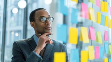 The thoughtful businessman analyzing ideas on colorful sticky notes. photo