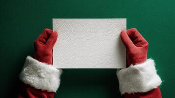 The festive hands of Santa holding a blank card against a green backdrop. photo