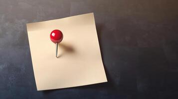 A red push pin on top of a piece of paper photo