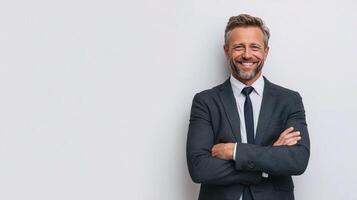 A smiling man in a suit and tie standing in front of a white wall photo