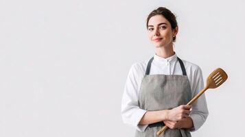 A woman in apron holding a wooden spoon photo