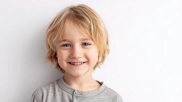 A young boy with blonde hair is smiling photo