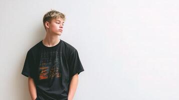 A young man leaning against a wall wearing a black t - shirt photo