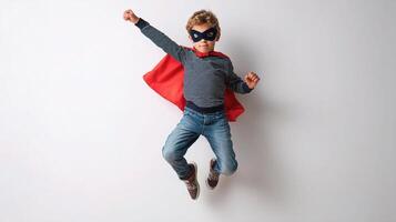 A young boy in a red cape and mask is jumping photo