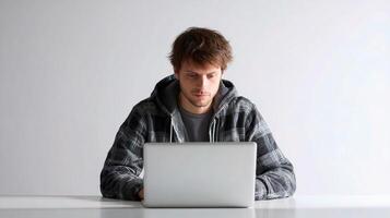 A man in a hoodie is sitting at a table with a laptop photo