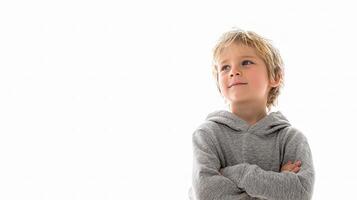 A young boy in a grey sweatshirt standing with his arms crossed photo