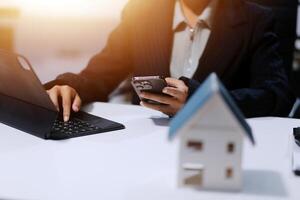 Businesswoman using laptop and mobile phone to search for a house photo