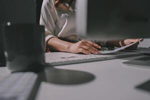 A person sitting at a desk with a computer and a keyboard photo