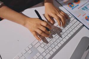 A person typing on a keyboard with a pen in their hand photo