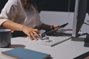 A woman is typing on a keyboard at a desk photo