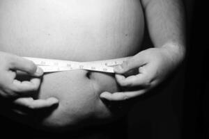 A black and white photo of a man measuring his stomach