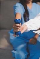 A woman in blue scrubs is holding a dumbbell photo