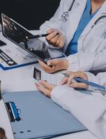 A doctor is using a tablet computer while another doctor is looking at it photo