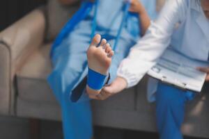A doctor is holding a foot with a blue bandage photo
