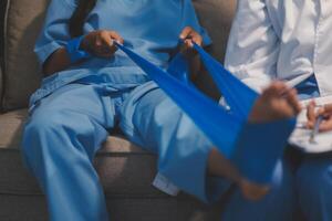 A woman in scrubs sitting on a couch with a blue bandage on her foot photo