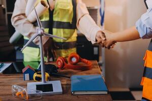 Two people shaking hands at a table with wind turbines photo