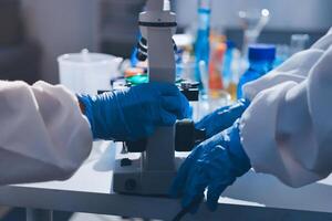 Two people in lab coats and gloves working on a microscope photo